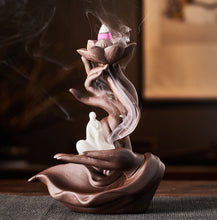 Load image into Gallery viewer, Thunderbolt Spiritual Books Back Flow Incense Burner on a table with Incense burning. A peaceful Monk sits in one of the hands in the mudra.